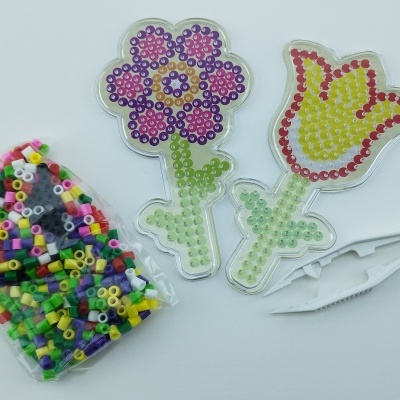 Peças de artesanato com miçangas coloridas e pinças brancas.