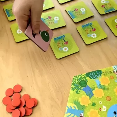Jogo de tabuleiro infantil com cartas quadradas e tabuleiro colorido na mesa