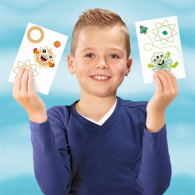 Menino seguro dois papéis com desenhos coloridos de caranguejos e símbolos atómicos