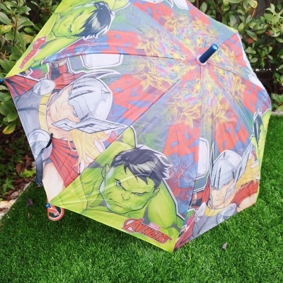 Guarda-chuva infantil colorido com personagens Avengers da Marvel sobre relva verde.