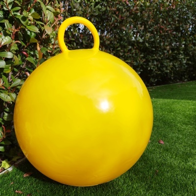 Bola amarela grande de borracha com asa para segurar em relva sintética ao ar livre