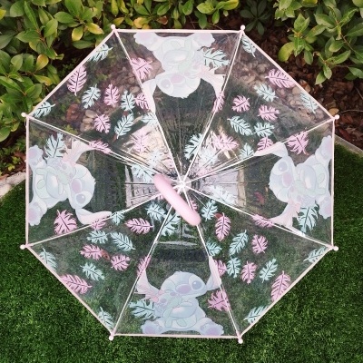 Guarda-chuva transparente com desenhos de folhas e personagem azul sobre relva