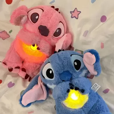 Dois peluches de Stitch rosa e azul com luz amarela na barriga sobre fundo branco com estrelas e corações