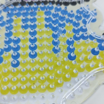 Objeto transparente com pinos coloridos formando padrão abstrato