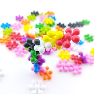 Peças de brincadeira plásticas coloridas em formas de flores num fundo branco