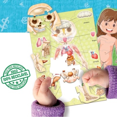 Puzzle educativo do corpo humano com partes recicláveis e mão de criança a montar