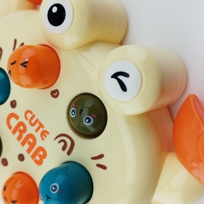 Brinquedo plástico de caranguejo amarelo e laranja com texto CUTE CRAB