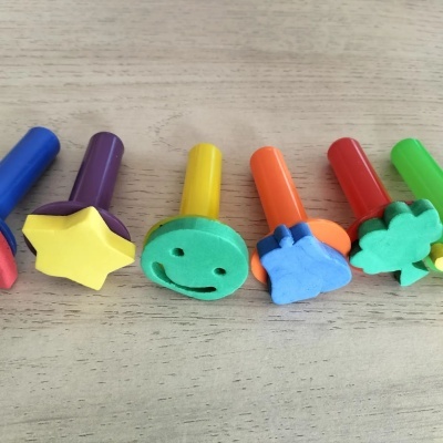 Carimbos de espuma coloridos com formas variadas sobre mesa de madeira