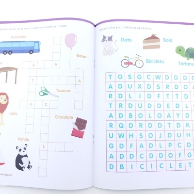 Livro infantil aberto com atividades coloridas de palavras cruzadas e caça-palavras em português.