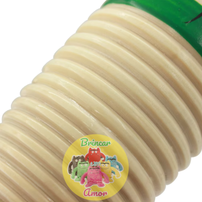 Embalagem amarela com bonecos coloridos e texto Brincar com Amor sobre objeto bege estriado.