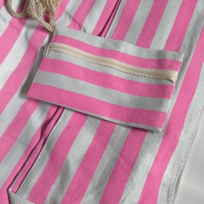 Toalha de praia às riscas rosa e branco com cordão de algodão ao lado
