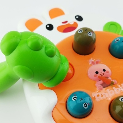 Brinquedo infantil colorido com alça verde e base branca com figura de coelho