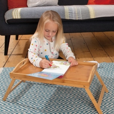 Mesa dobrável de madeira clara com criança desenhando sobre tapete azul geométrico