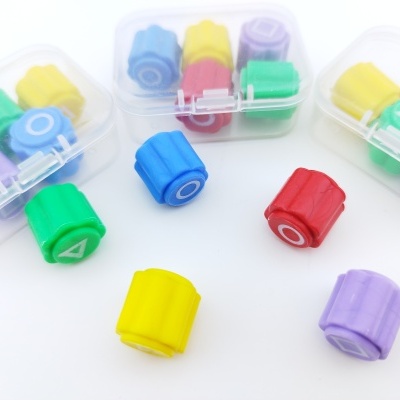 Carimbos coloridos de plástico com letras e formas em caixas transparentes