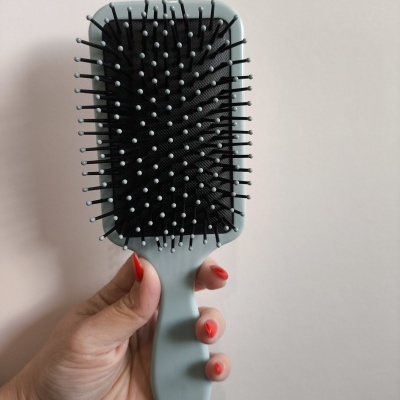 Escova de cabelo raquete cinza com cerdas pretas e pontas brancas