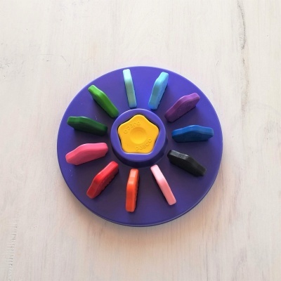 Lápis de cor triangulares num suporte redondo roxo com peça central amarela