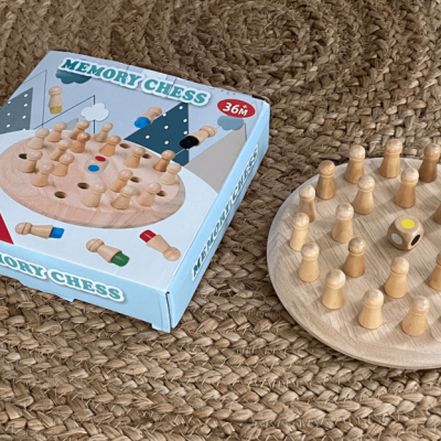 Jogo memory chess em madeira com caixa azul e branco numa superfície de tecido entrelaçado castanho.