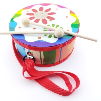 Tambor de brinquedo colorido com flor e baquetas em fundo branco