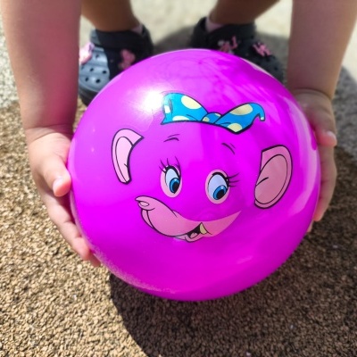 Bola cor-de-rosa com desenho de elefante e mãos de criança segurando.