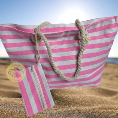 Saco de praia rosa e branco com alças de corda na areia