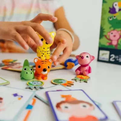 Peças de madeira de animais coloridos e cartas de um jogo infantil sobre uma mesa branca