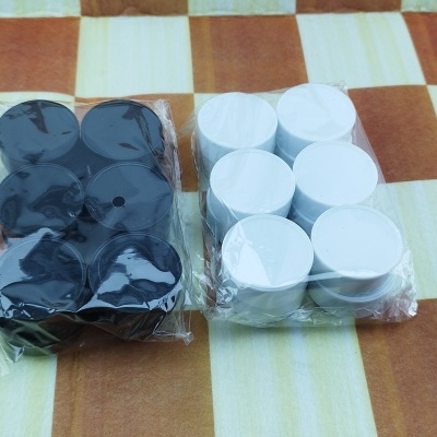 Peças de jogo pretas e brancas embaladas em plástico sobre um tabuleiro de xadrez castanho e creme