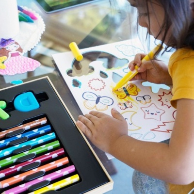 Conjunto de lápis coloridos em caixa com criança a pintar folhas