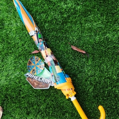 Guarda-chuva infantil fechado amarelo com padrão Minecraft sobre relva verde artificial