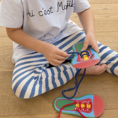 Criança a brincar com brinquedo de sapatos coloridos sentada no chão de madeira