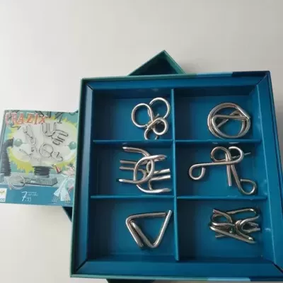 Conjunto de puzzles metálicos em tabuleiro azul com caixa colorida com texto CRAZY