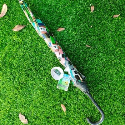 Guarda-chuva fechado com padrão colorido estilo Minecraft sobre relva verde