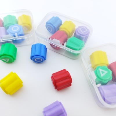 Carimbos coloridos de plástico com formas geométricas em caixas transparentes