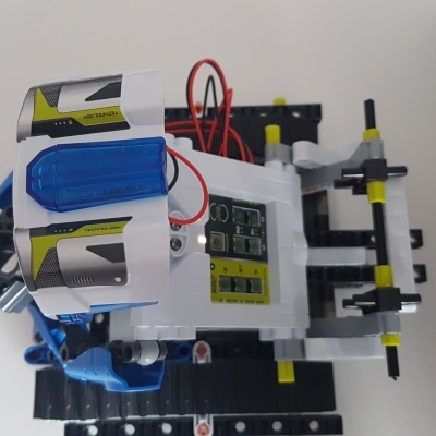 Brinquedo robô de peças plásticas coloridas com fios vermelhos em fundo branco