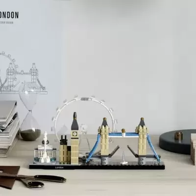 Miniatura da Tower Bridge de Londres feita de blocos de construção coloridos sobre uma base preta numa mesa com livros e relógio