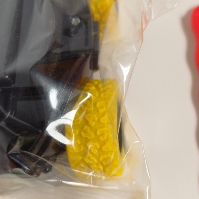 Brinquedo com rodas amarelas e corpo preto em embalagem plástica transparente