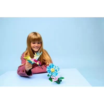 Menina brinca com brinquedo de construção colorido de beija-flor e flor azul na mesa