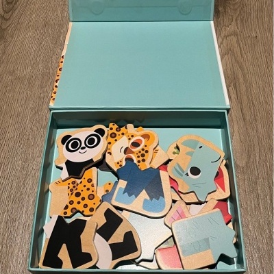 Peças de quebra-cabeças de madeira de animais dentro de uma caixa azul sobre uma mesa de madeira