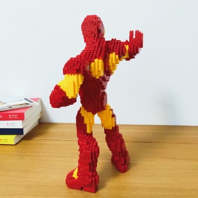 Figura do Homem de Ferro feita com blocos tipo LEGO em vermelho e amarelo sobre mesa de madeira clara
