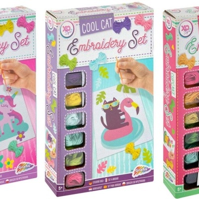 Três caixas de conjuntos de bordado com temas unicórnio, gato e cupcake e fios coloridos visíveis