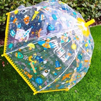 Guarda-chuva transparente com padrão colorido espacial sobre relva