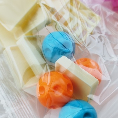 Barras de chocolate branco com contas plásticas coloridas em embalagem transparente