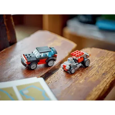 Dois carros de brinquedo de blocos plásticos em cima de mesa de madeira com livro aberto