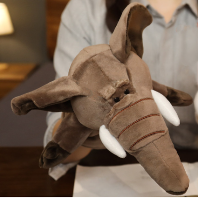 Pelúcia de elefante castanha com presas brancas sendo segurada por pessoa