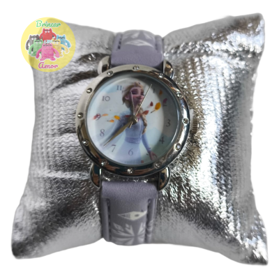 Relógio de pulso com mostrador redondo e bracelete lilás com padrão branco sobre almofada prateada