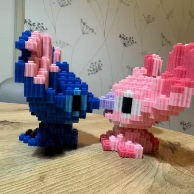 Duas figuras de blocos de encaixe em azul e rosa sobre uma mesa de madeira clara
