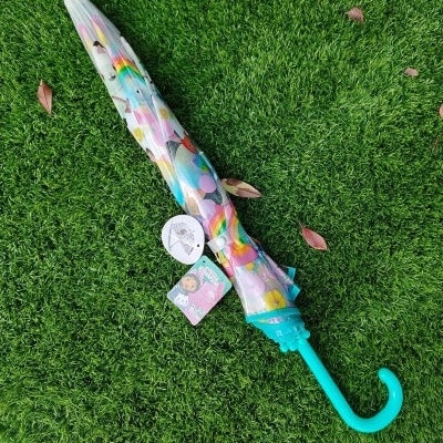 Guarda-chuva infantil fechado com estampas coloridas sobre relva verde