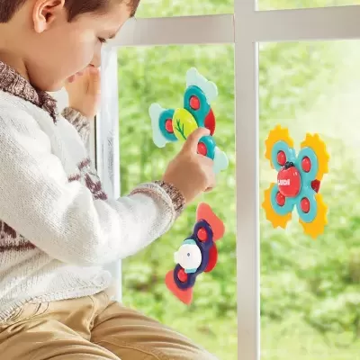 Menino brincando com brinquedos de plástico coloridos com ventosas na janela