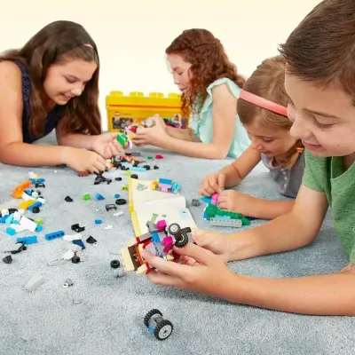 Crianças montando brinquedos com blocos LEGO coloridos no chão