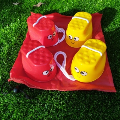 Sapatos de brincar coloridos com olhos desenhados sobre saco vermelho na relva