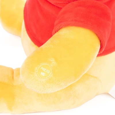 Pelúcia amarela com camisola vermelha e texto 'PRESS ME'. 